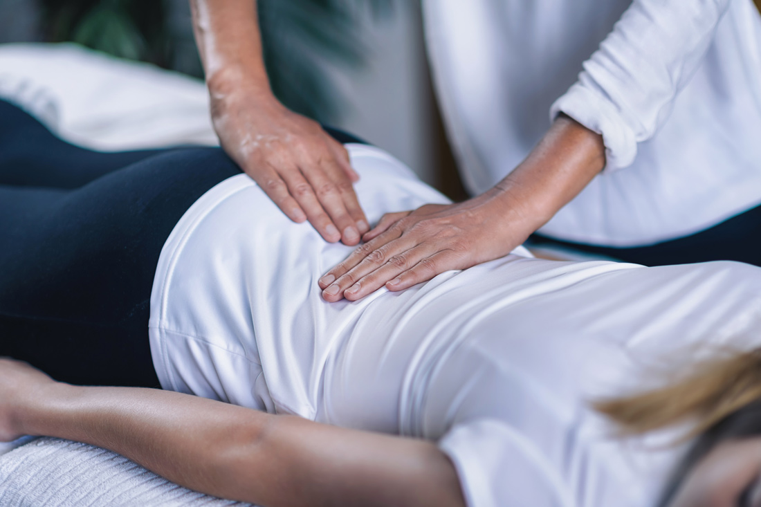 Reiki practicioner holding hands over clients lower back.