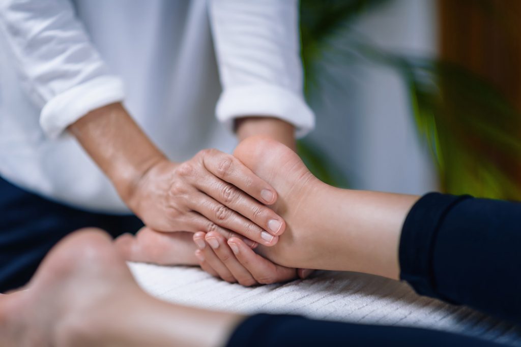 Reiki practioncer gently holding foot during session.